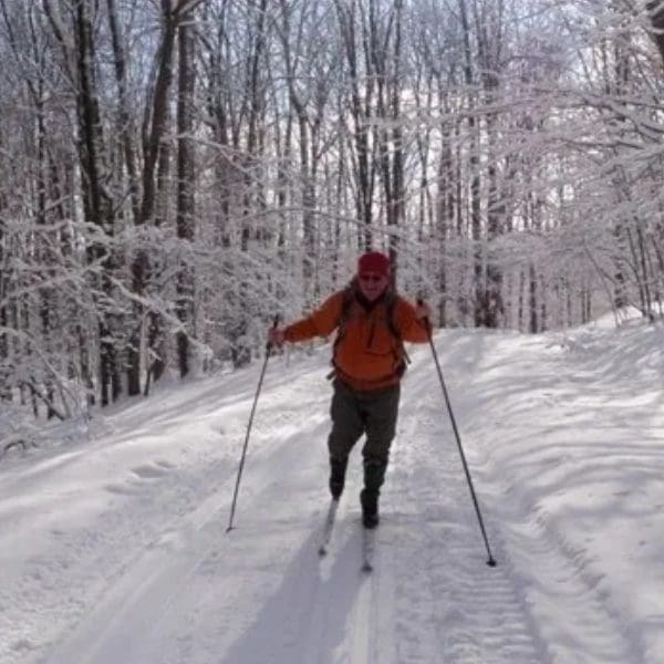 A man is cross country skiing in the woods.