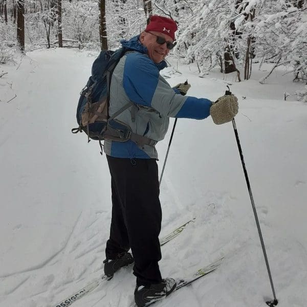 A man in blue jacket standing on snow covered ground.