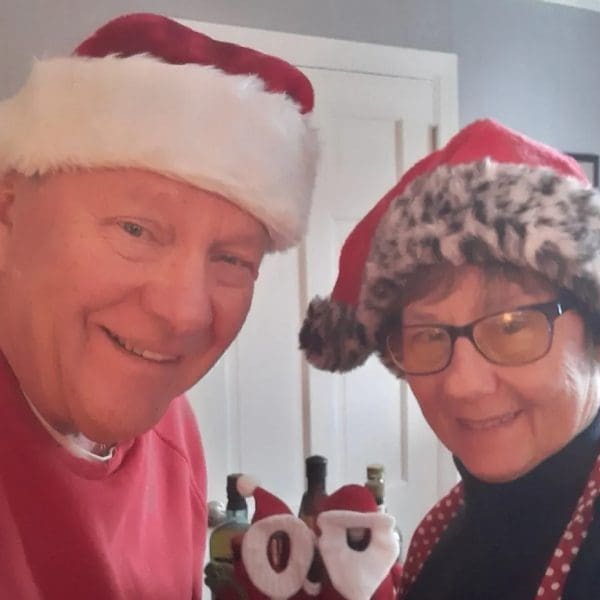 A man and woman wearing christmas hats.
